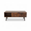 A mid-century modern wooden coffee table with a rich, distressed brown finish, featuring a single drawer with a pull handle and an open side shelf, supported by tapered black legs on a concrete surface.